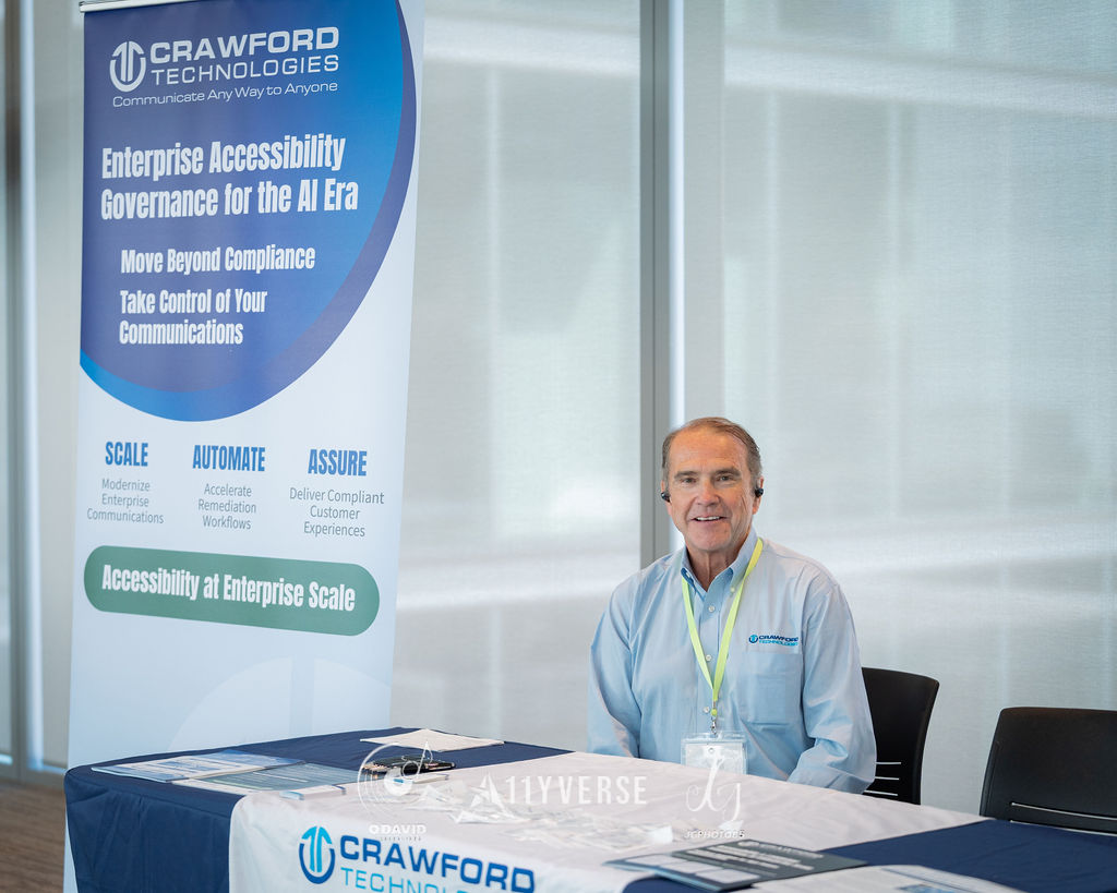 A person wearing a headset sits smiling behind a Crawford Technologies booth, beside a banner about enterprise accessibility governance.